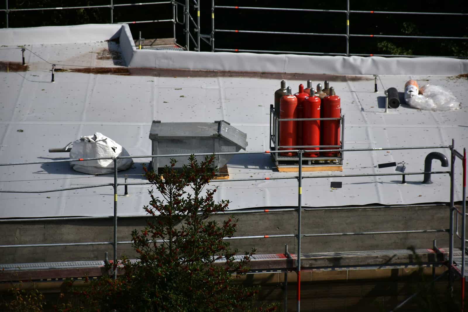 Flat roof installation with white membrane and torch-down equipment