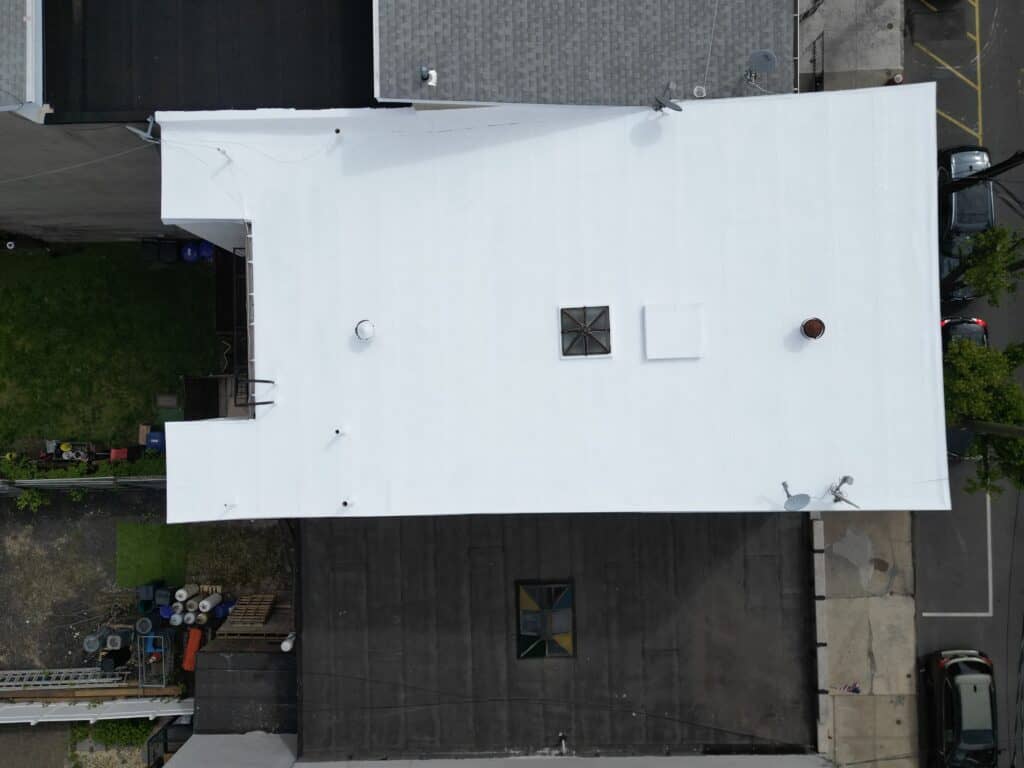 Drone shot of bright white reflective silicone-coated flat roof in Hoboken, NJ — fully sealed and warranty-backed silicone restoration by Gaby Roofing Flat Roof Specialist.