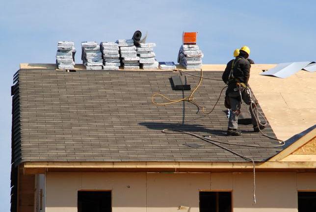 Workers on a shingle roof for a commercial roofing job