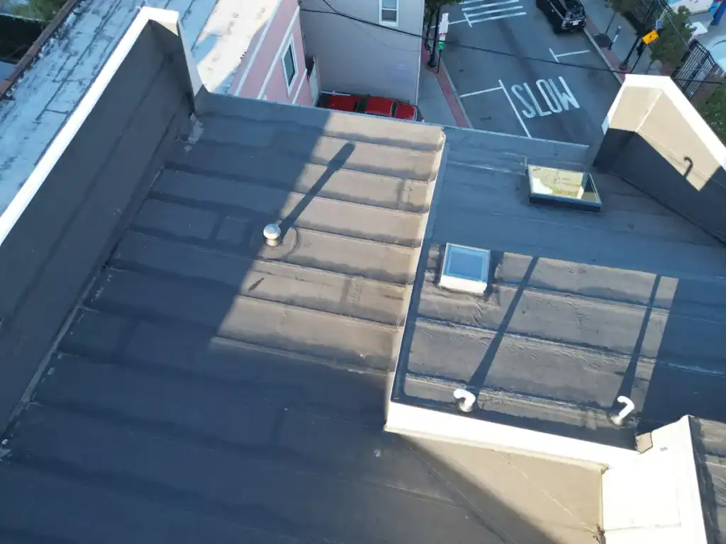 Aerial view of new white parapet wall coping and skylight flashings on a torch-down flat roof in Union City, New Jersey