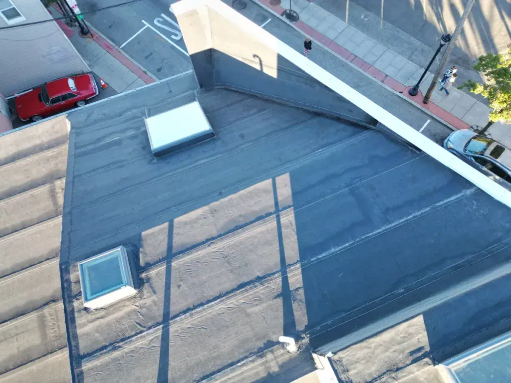 Aerial view from above a Union City NJ intersection showing a completed torch-down flat roof with flashed skylight and new edge metal