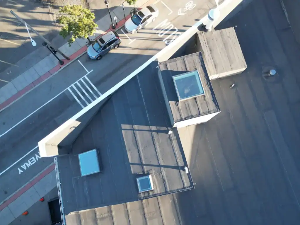 Overhead view of a new modified bitumen torch-down membrane with sealed seams and flashed skylights on a Union City NJ flat roof