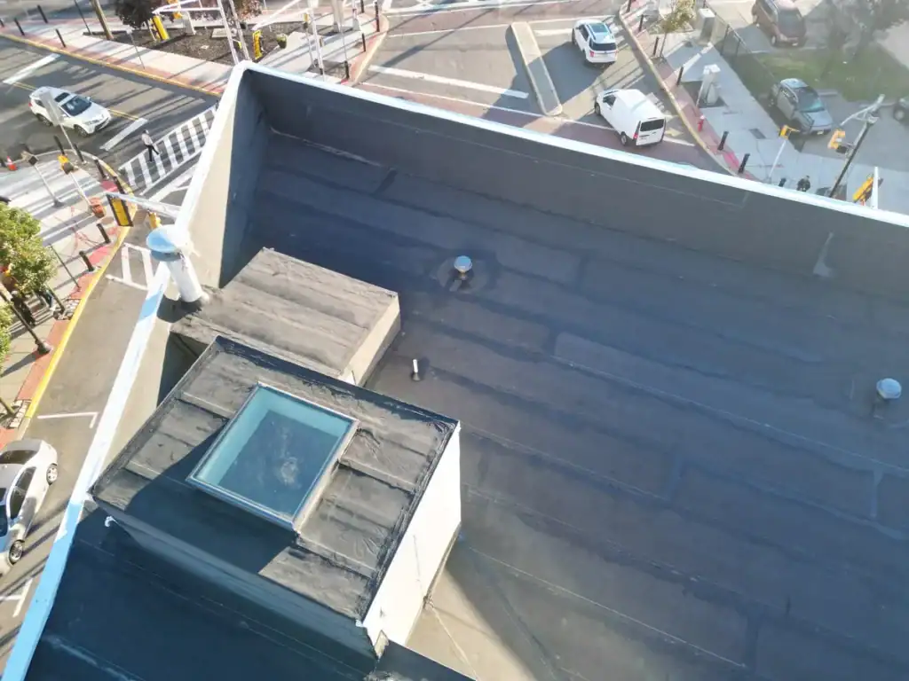 Close-up aerial of a torch-down flat roof in Union City NJ showing a skylight curb flashed with modified bitumen and new perimeter coping
