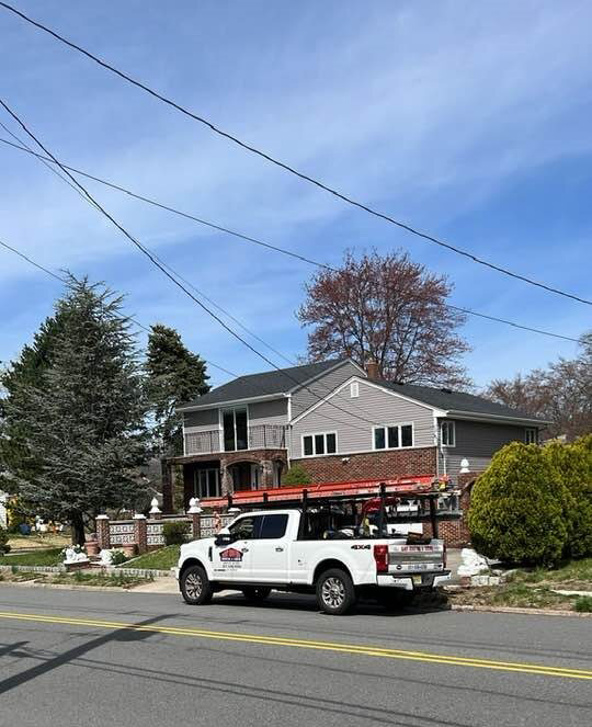 Gaby Roofing flat roof specialist branded pickup truck and ladder rack parked at a North Jersey, NJ residential job site