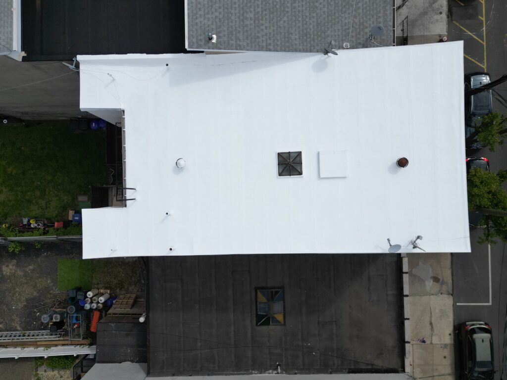 Drone shot of bright white reflective silicone-coated flat roof in Hoboken, NJ — fully sealed and warranty-backed silicone restoration by Gaby Roofing Flat Roof Specialist.
